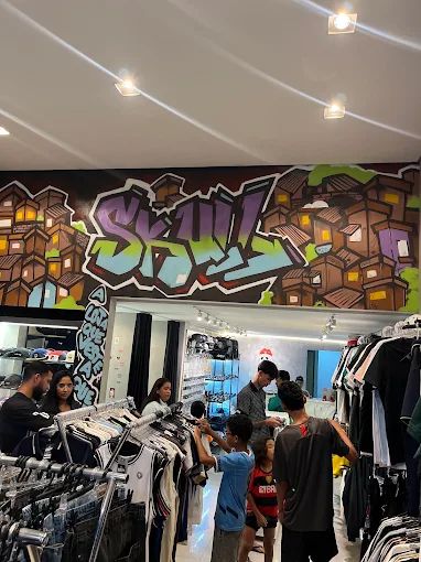 Interior da loja com clientes e mural grafitado